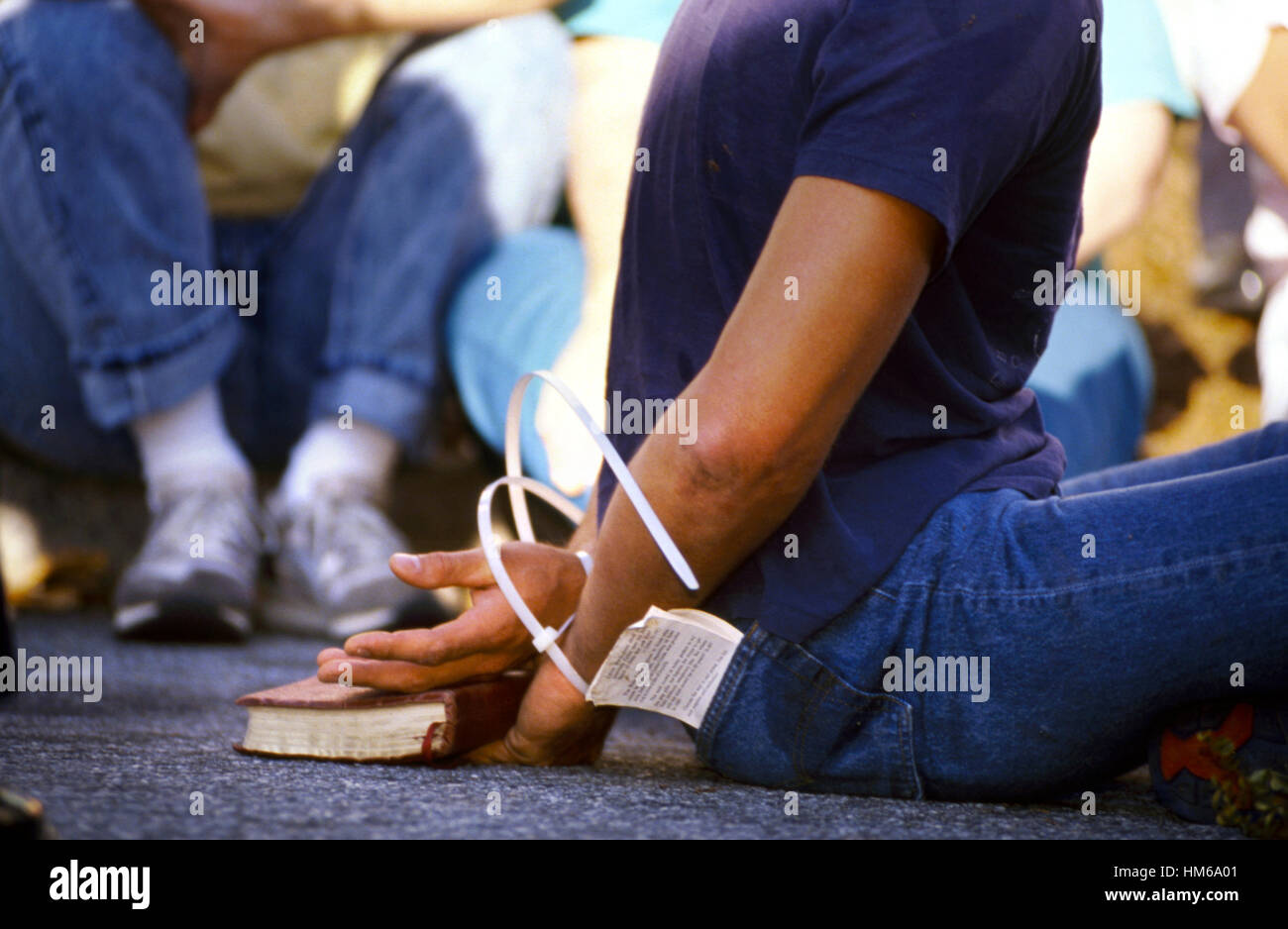 A pro life demonstrator holds his Bible as he is arrested and put in flex cuffs outside an abortion clinic Stock Photo