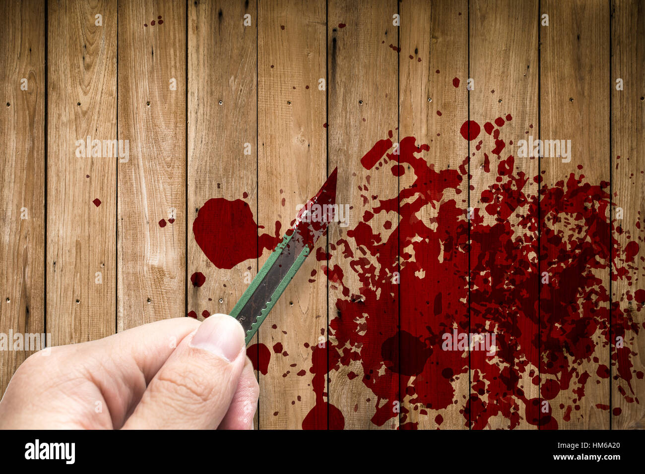 hand hold rusty knife cutter with grunge of blood and gore on wood background, blood splash on wood wall, kill and murder concept. Stock Photo