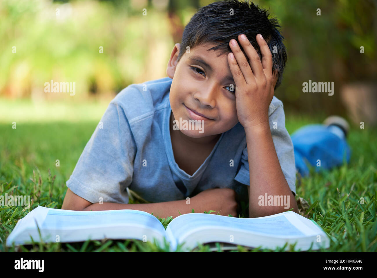 kid tired holding his head while reading a book Stock Photo