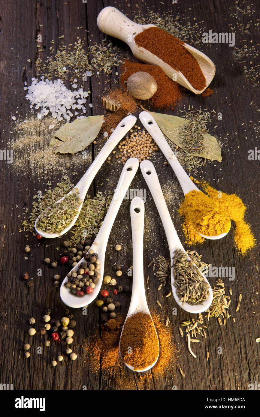 Various dried spices on small spoons, paprika, colorful peppercorns, basil, bay leaves, coarse salt, nutmeg, oregano, turmeric Stock Photo