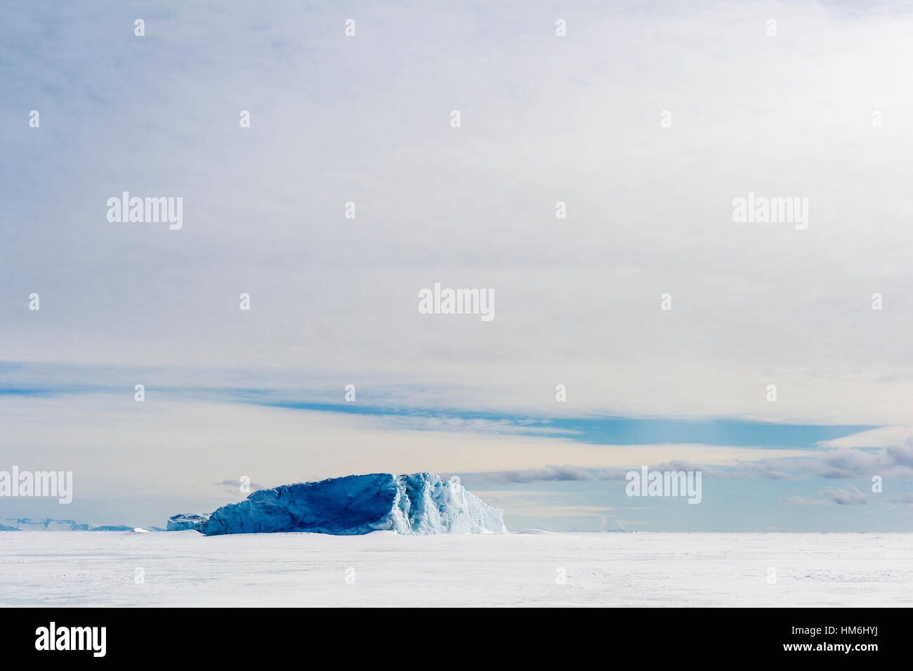 An enormous iceberg trapped in frozen sea ice. Stock Photo