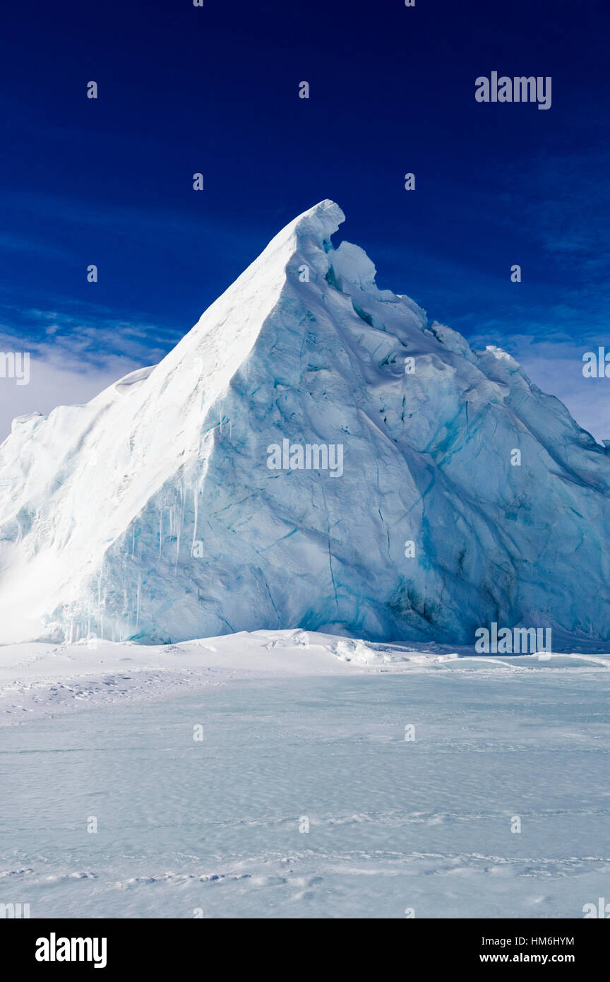 An enormous jagged iceberg trapped in frozen sea ice. Stock Photo