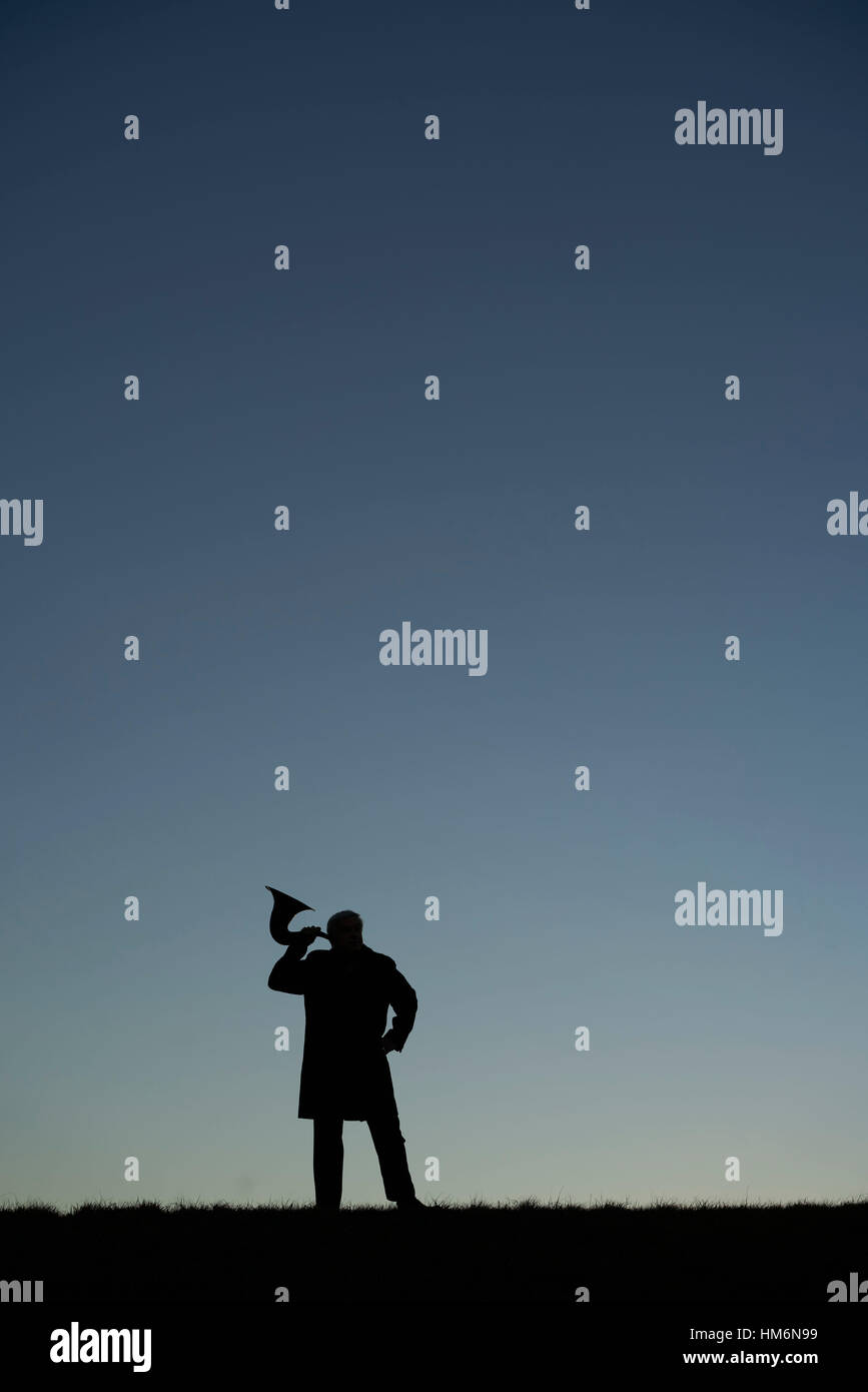 silhouette of a man on a mountain with eartrumpet at dusk Stock Photo