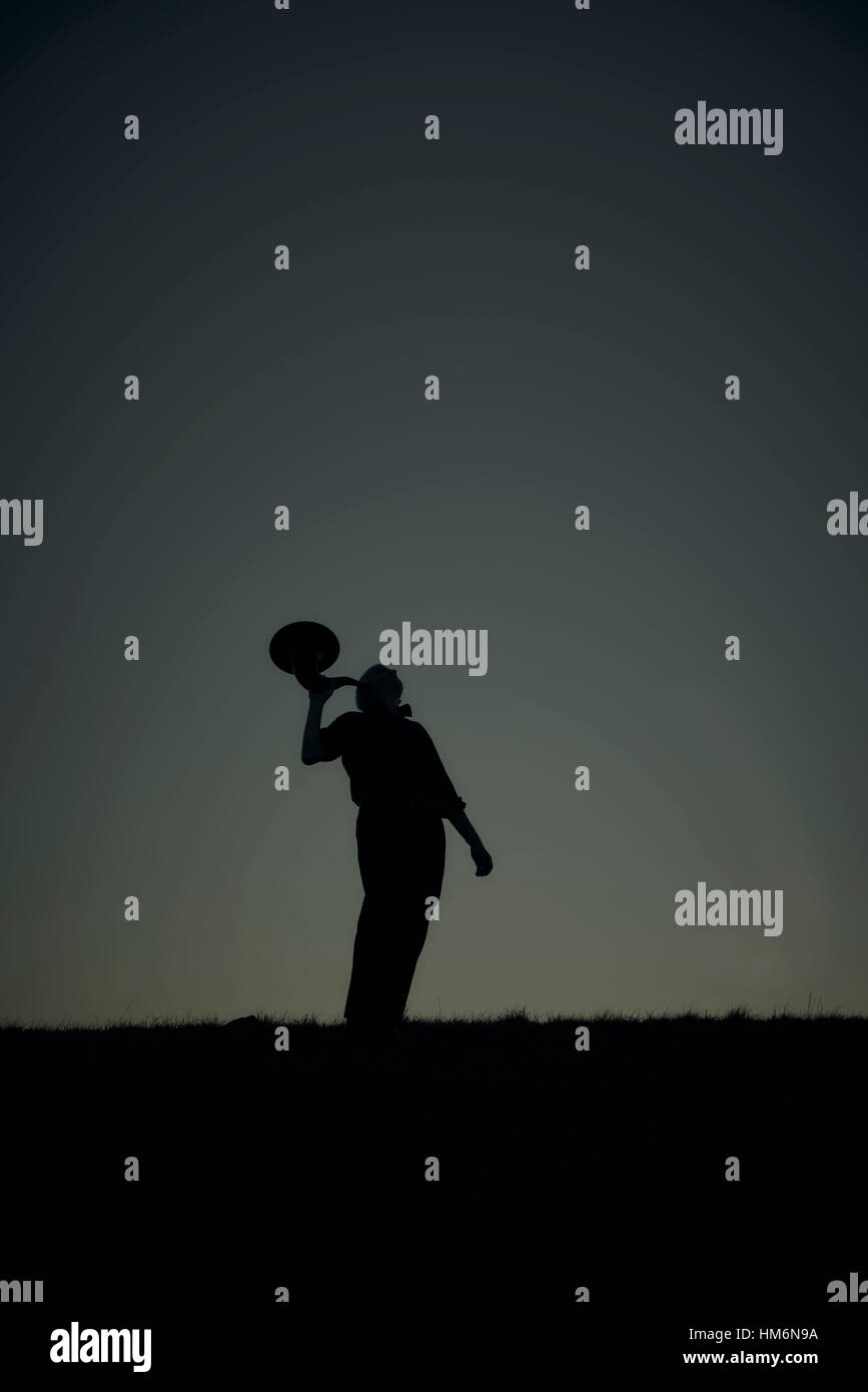 silhouette of a man on a mountain with eartrumpet at night Stock Photo