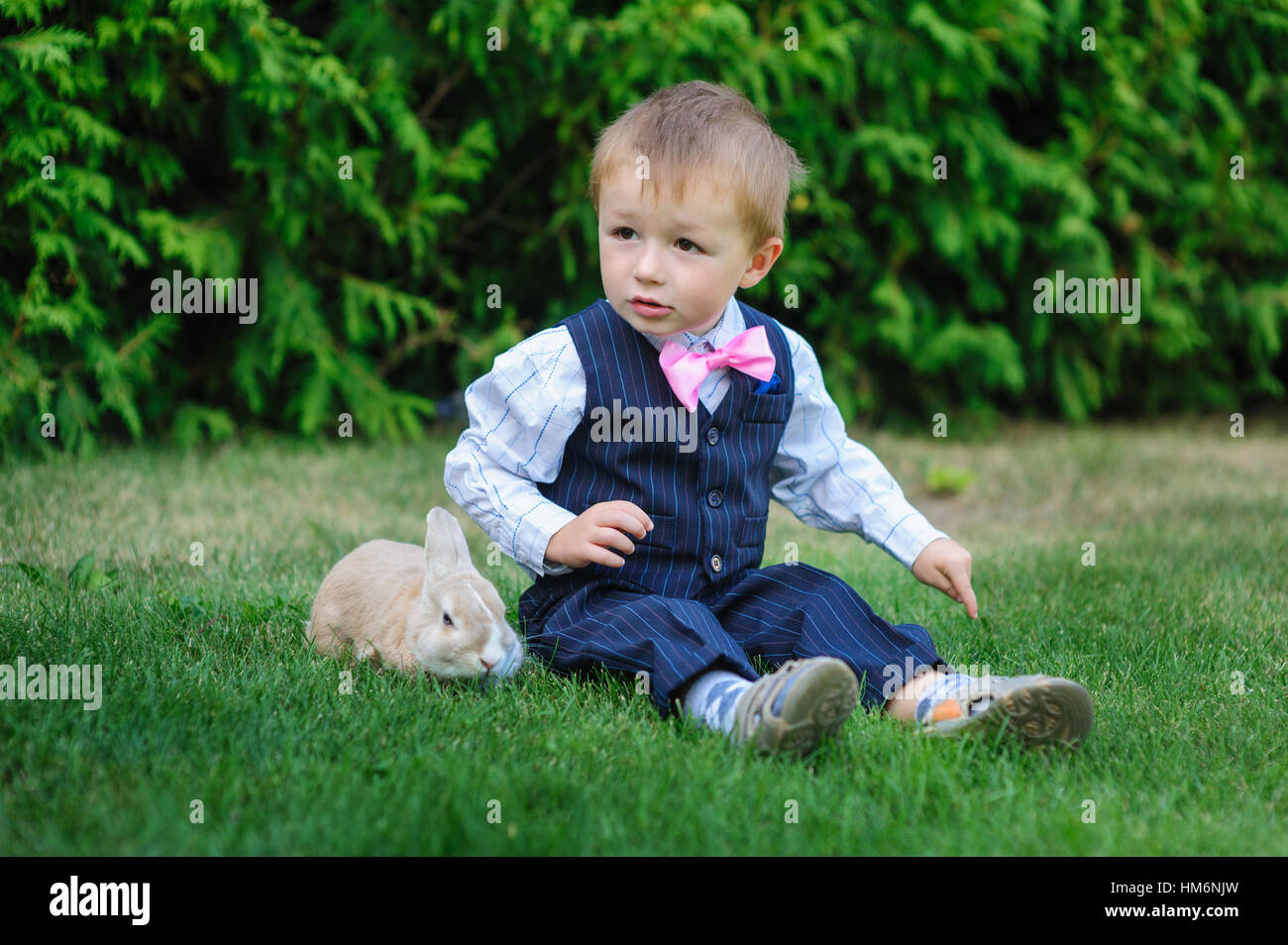 little boy sitting on the grass with a rabbit Stock Photo