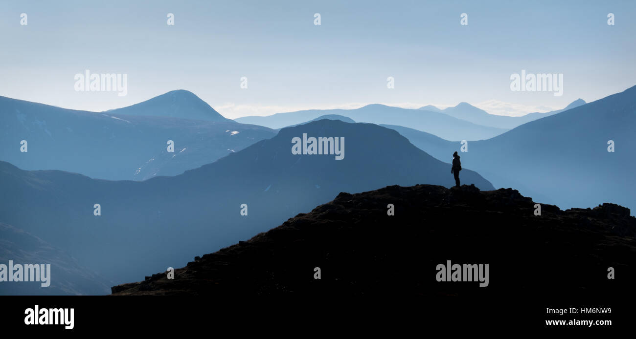 Hillwalker on Buchaille Etive Beag in the Scottish Highlands, hazy mountains receding into distance Stock Photo