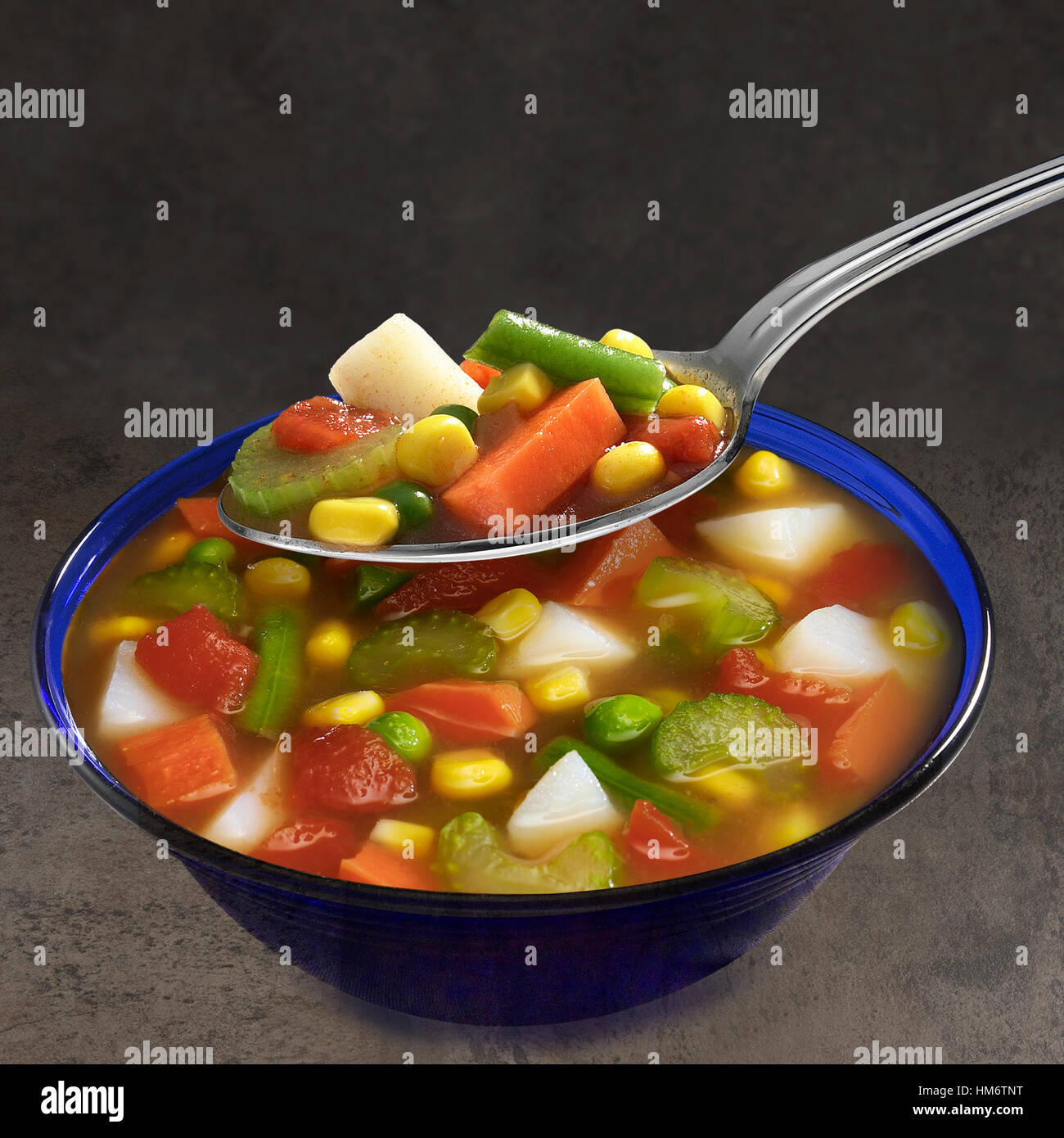 Hearty Vegetable Soup in blue bowl with spoon Stock Photo