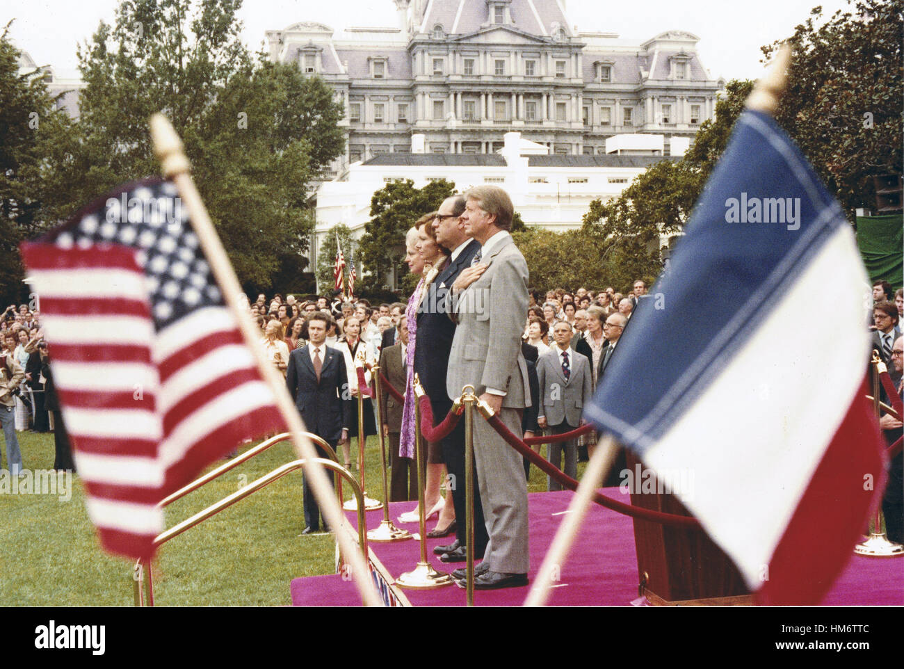 Framed by the flags of the United States of America and the Republic of France, US President Jimmy Carter and first lady Rosalynn Carter and Prime Minister Raymond Barre of France and his wife, Eve, stand at attention during the full honor arrival ceremon Stock Photo