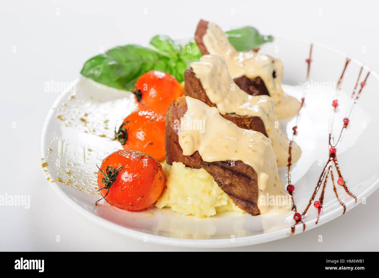 Baked mutton meat with creamy sauce, mashed potato and cherry tomatoes Stock Photo
