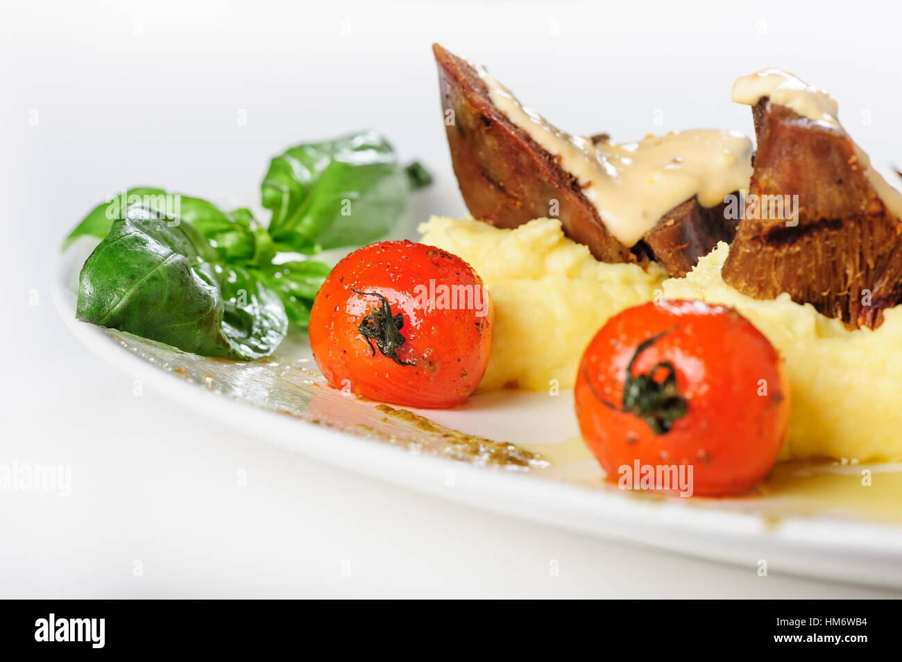Baked mutton meat with creamy sauce, mashed potato and cherry tomatoes Stock Photo