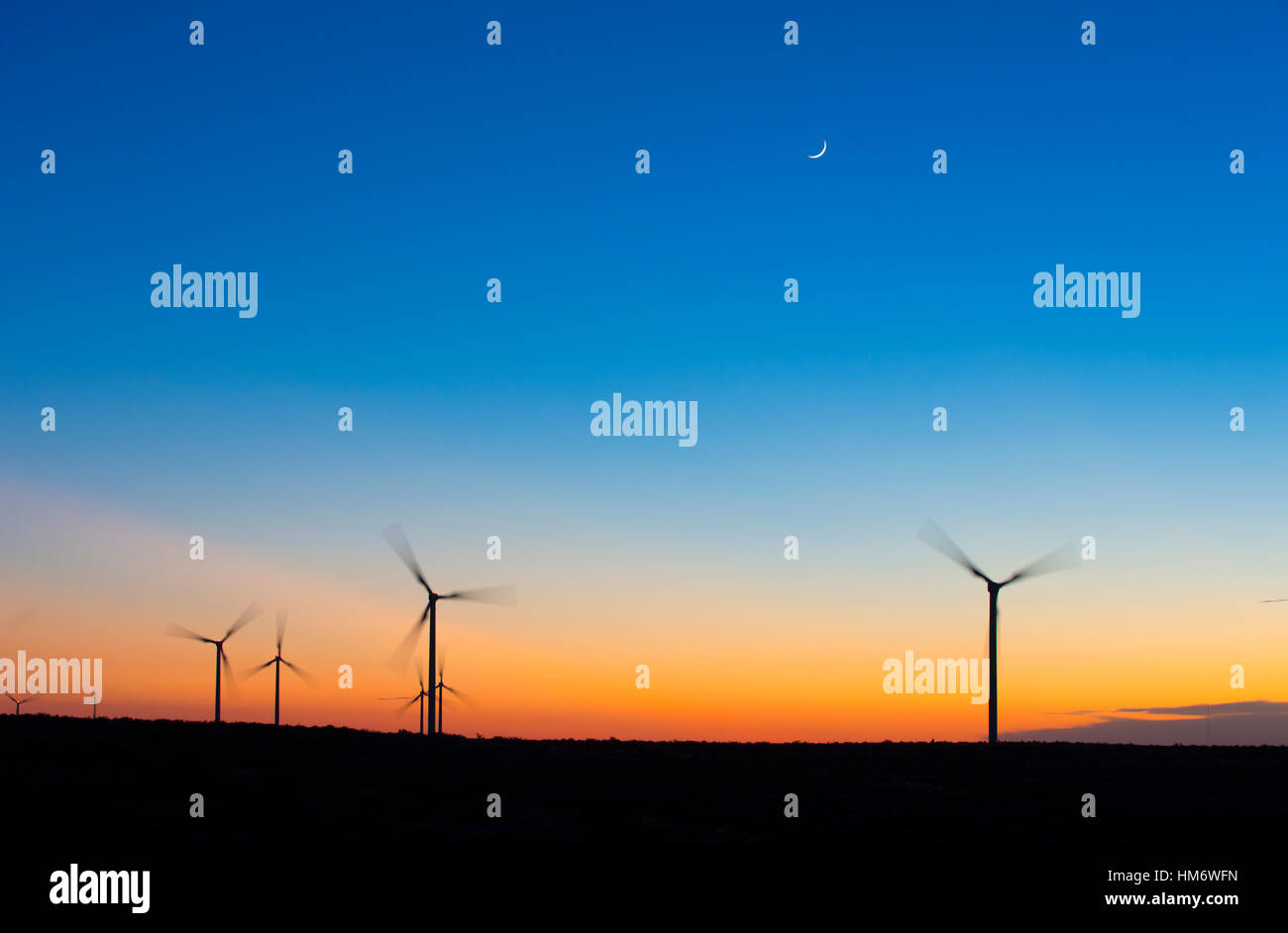 Silhouette wind turbines spinning against blue sky during sunset Stock ...