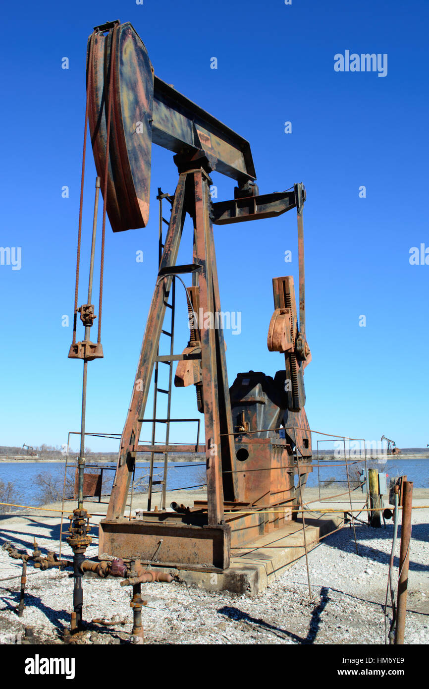 Rusty Oilfield Pumpjack (rocking horse) over a wellhead. Clear blue sky