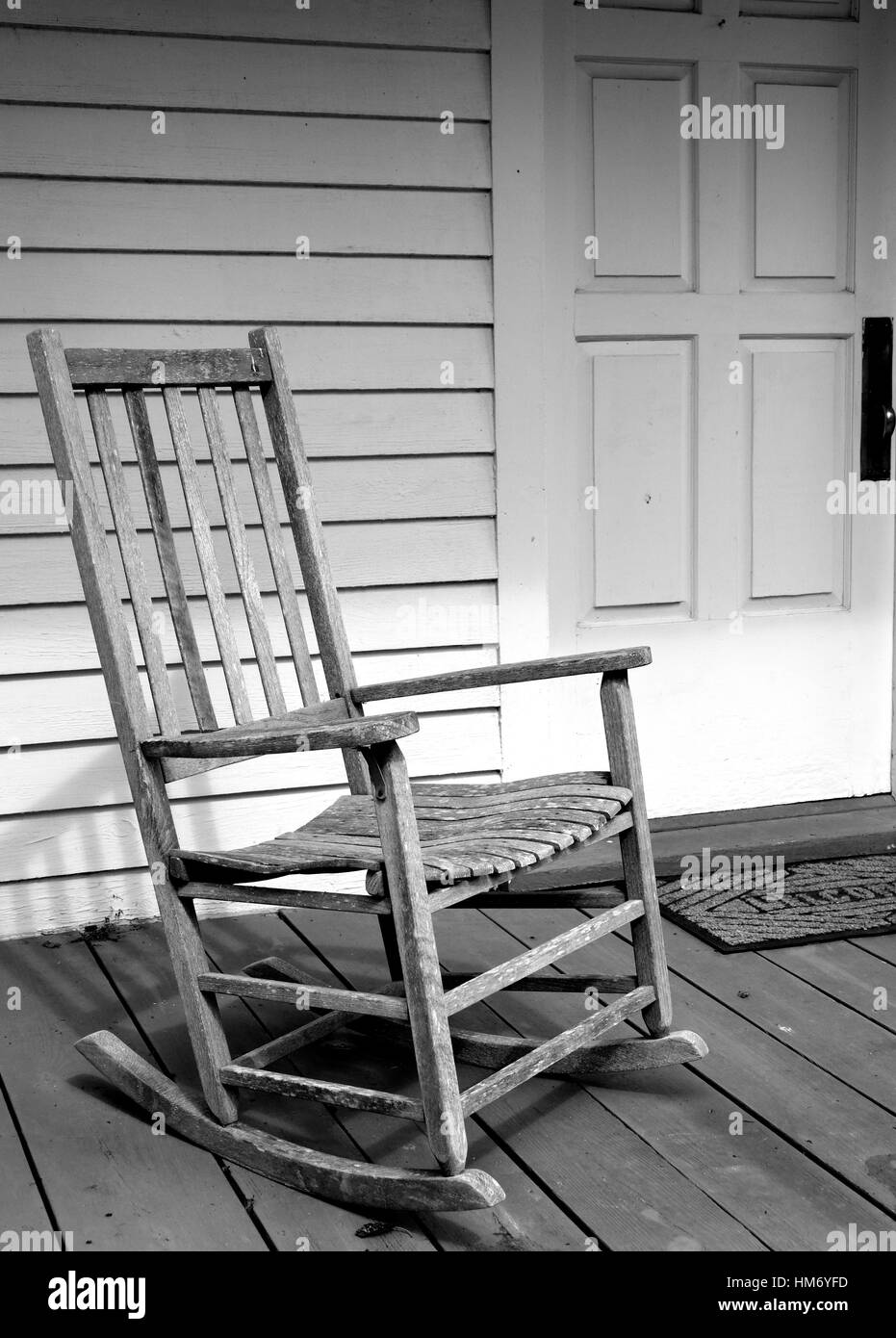 Weathered, vintage rocking chair on the porch of a white house. Stock Photo