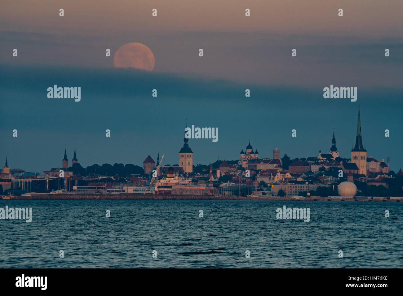Full moon over Old town of Tallinn city, Estonia. Moonset before sunrise Stock Photo