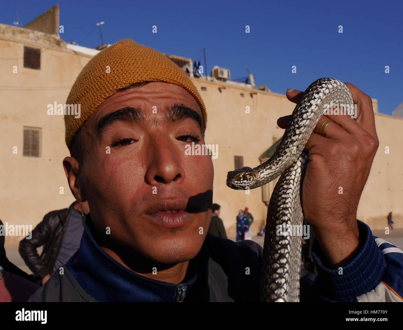 Close up portrait of Moroccan snake charmer holding snake close to his face in Place-el-Hedime, main square of the imperial city of Meknes, Morocco Stock Photo