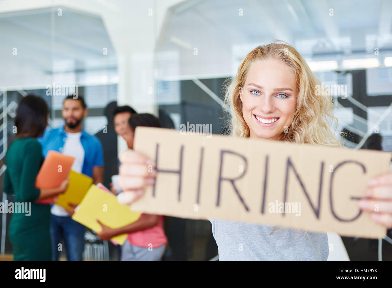Woman in start-up holding sign as hiring advertising Stock Photo