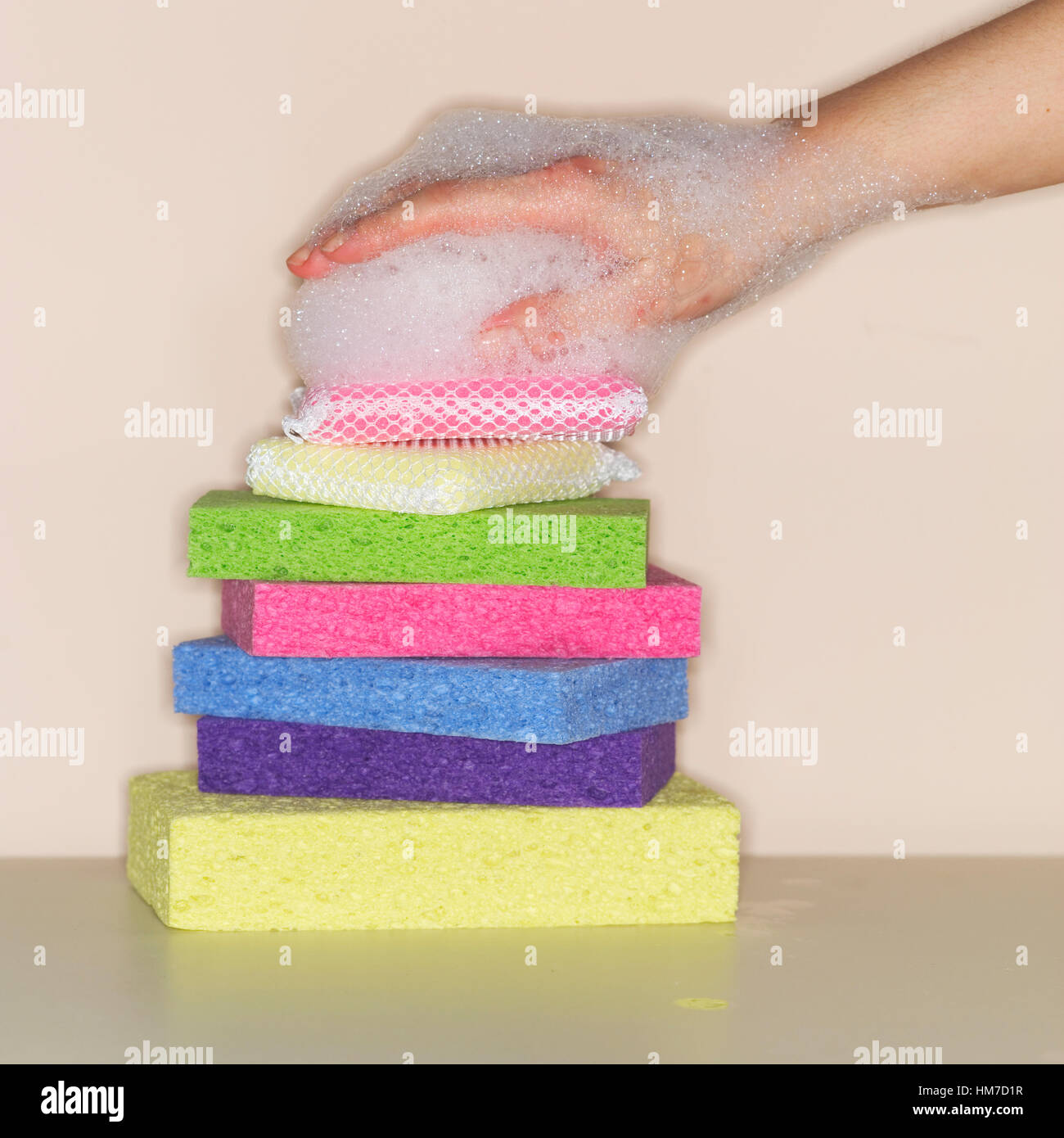 Female hand covered in foam on stack of sponges Stock Photo