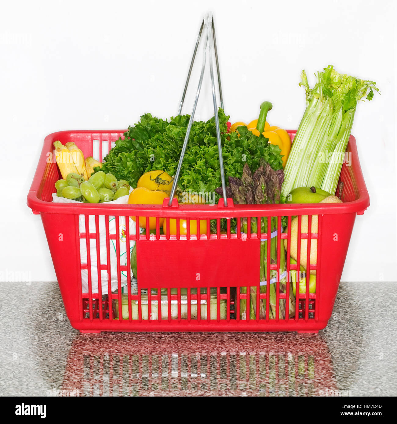 Fruits and vegetables in grocery basket on countertop Stock Photo