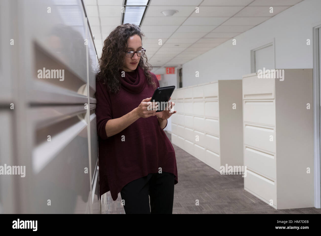 Young woman using digital tablet in corridor Stock Photo