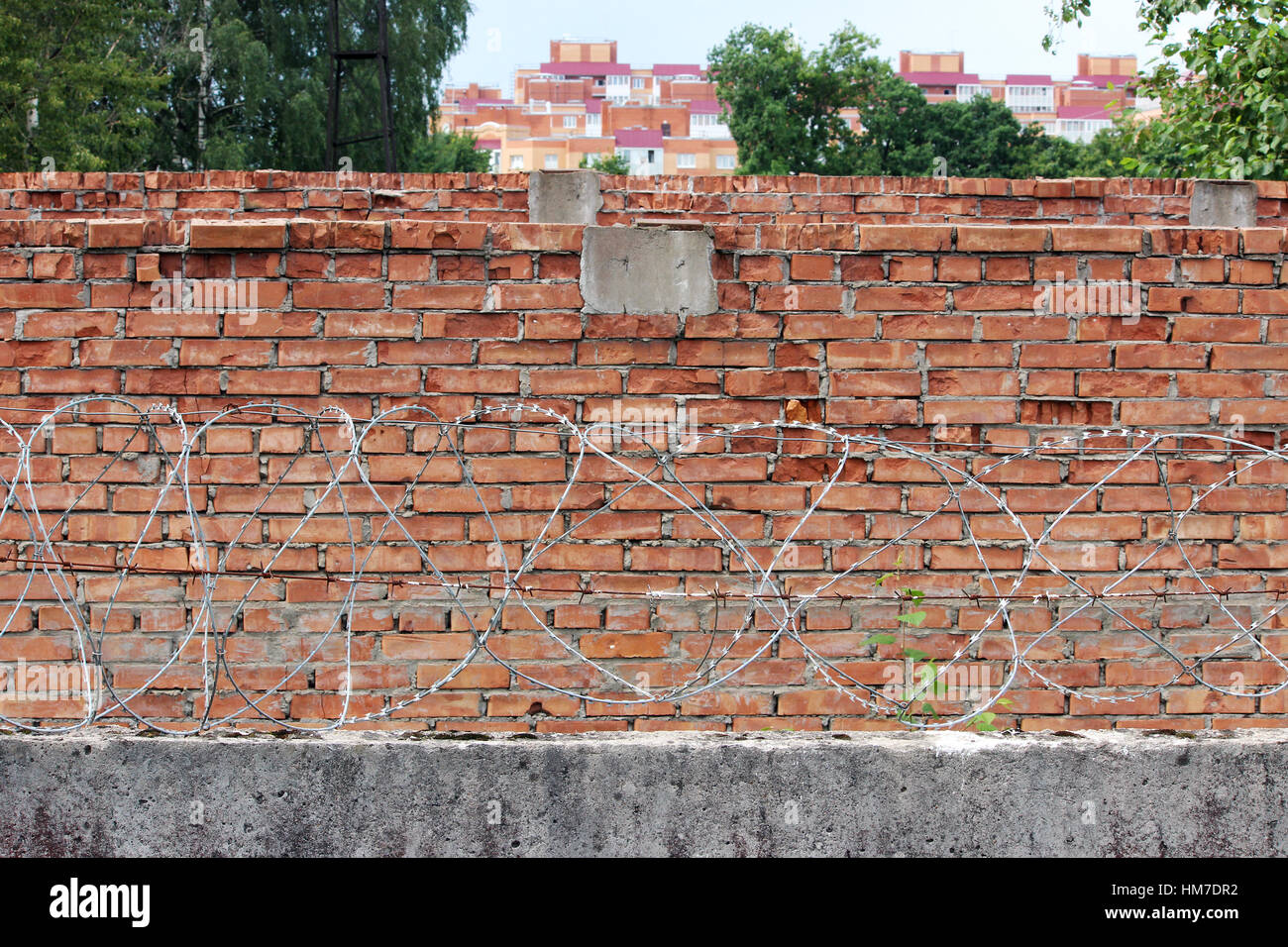 Barbed wire on a background of red brick wall Stock Photo - Alamy