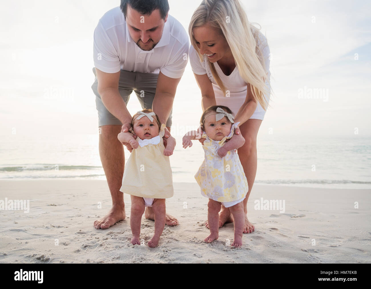 Happy family with two baby girls (2-5 months) at beach Stock Photo