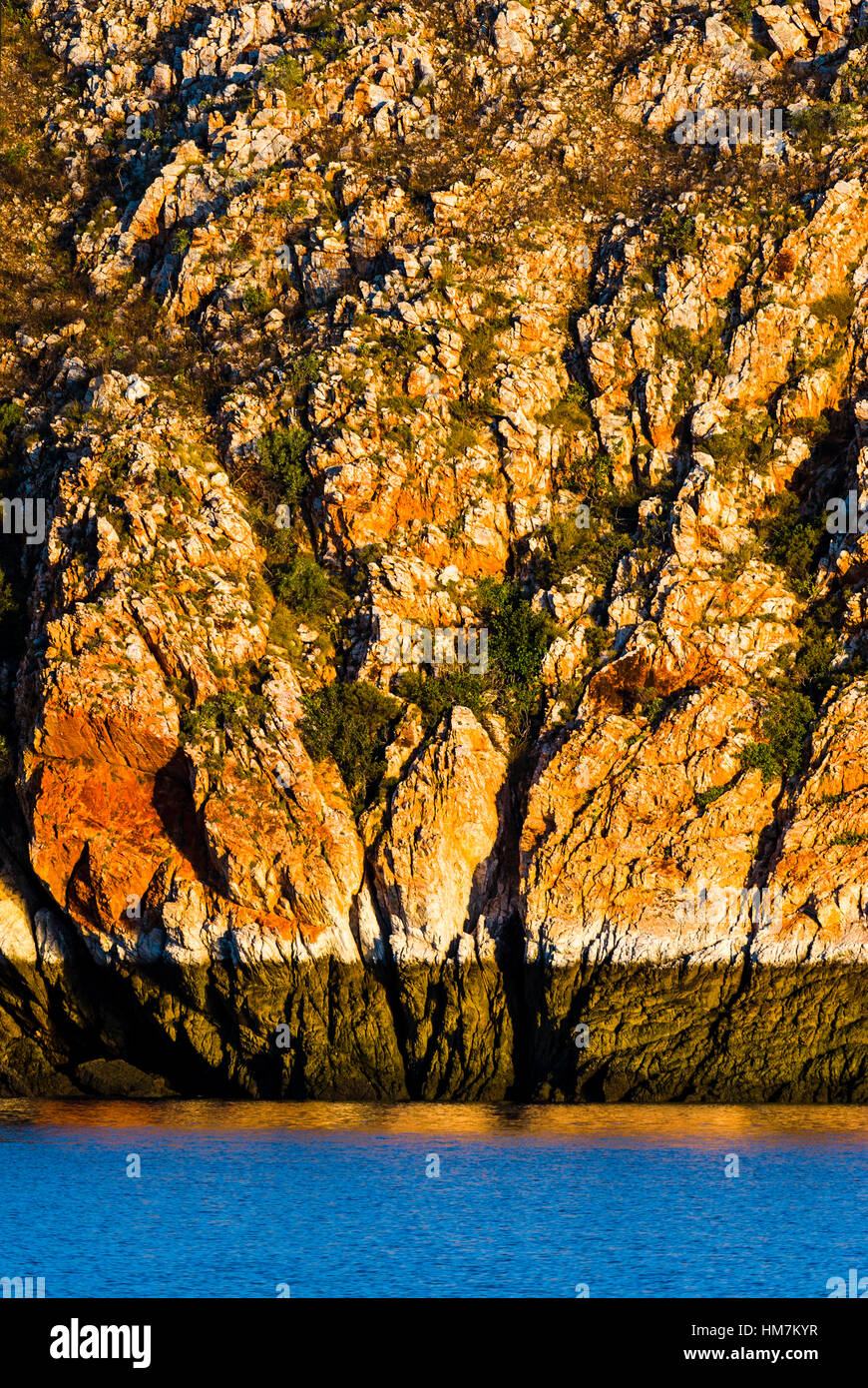 The hide tide mark and cyanobacteria stain on a sandstone cliff above the ocean. Stock Photo