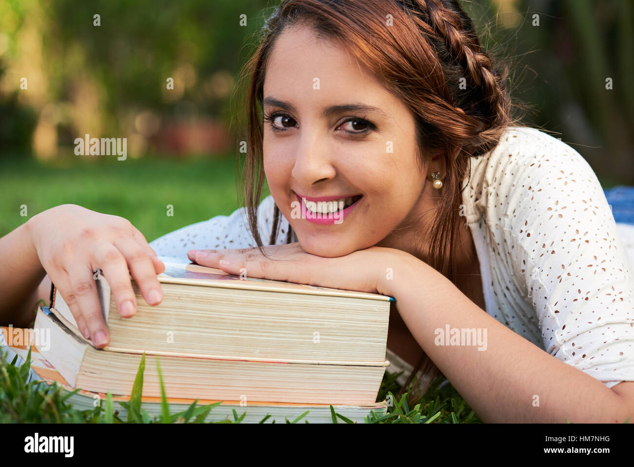 woman resting on pile of books and smiling Stock Photo - Alamy
