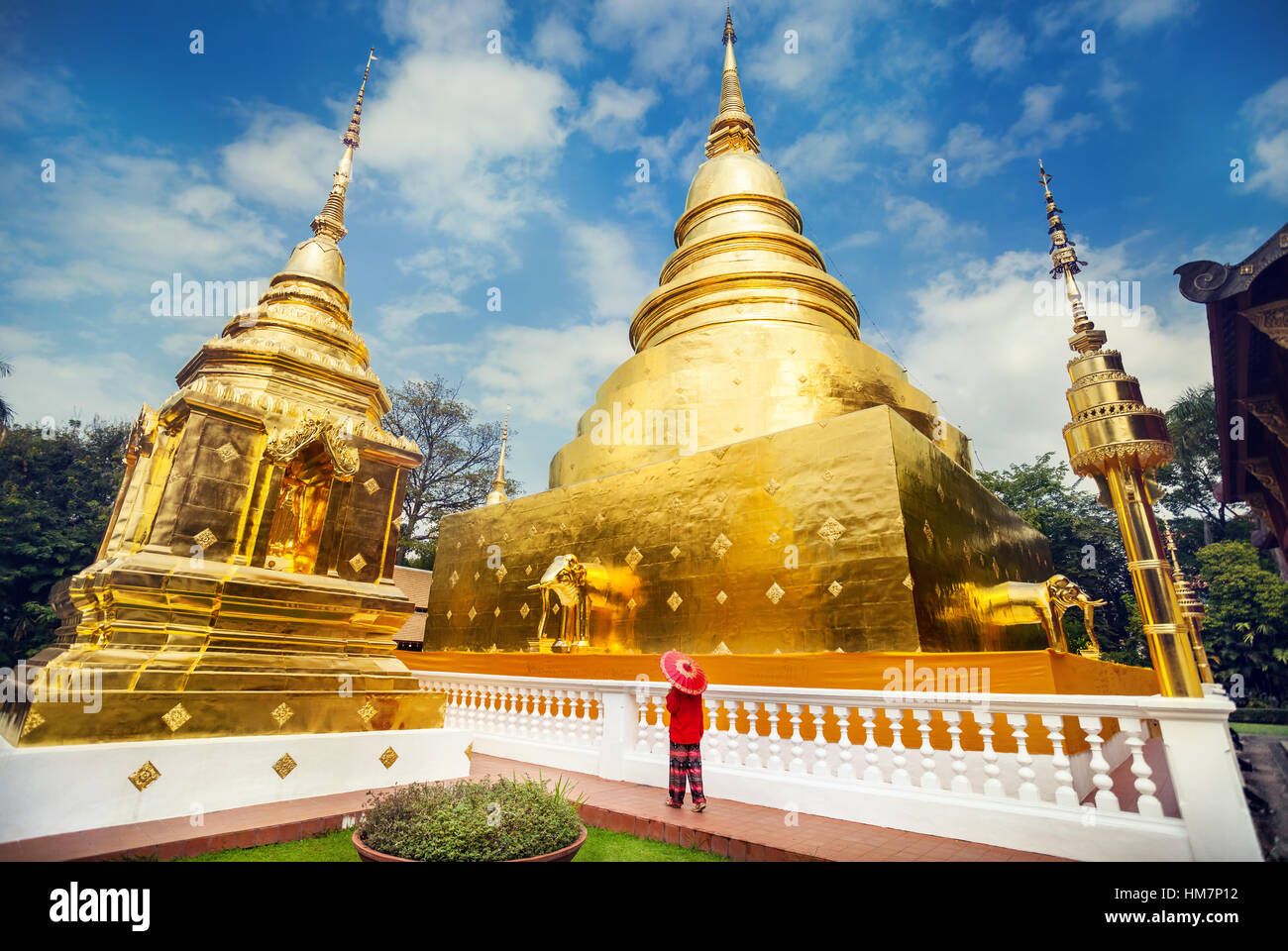Woman tourist with red traditional Thai umbrella near Golden Stupa at temple Wat Phra Singh in Chiang Mai, Thailand Stock Photo