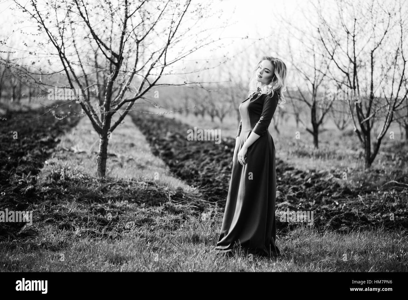 Yong elegance blonde girl at green dress on the garden in spring Stock