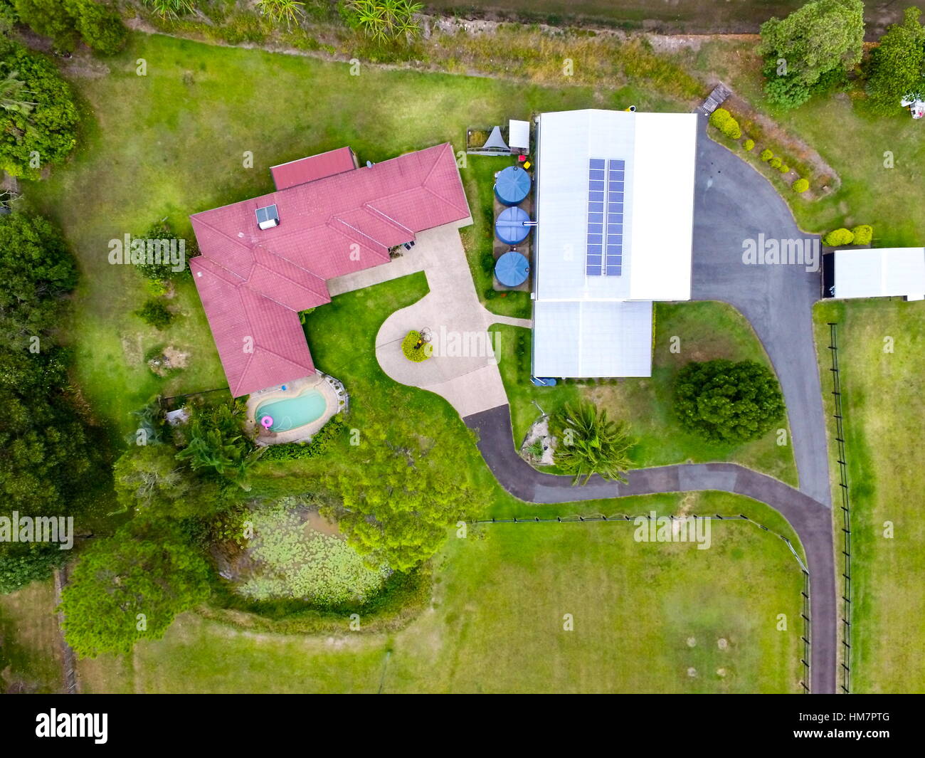 Aerial view looking down on a farm house with red roof and water tanks, in Queensland, Australia. Stock Photo