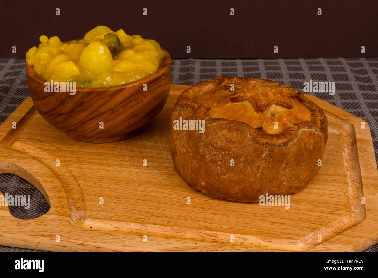 Piccalilli relish in a wooden bowl on a board. Stock Photo