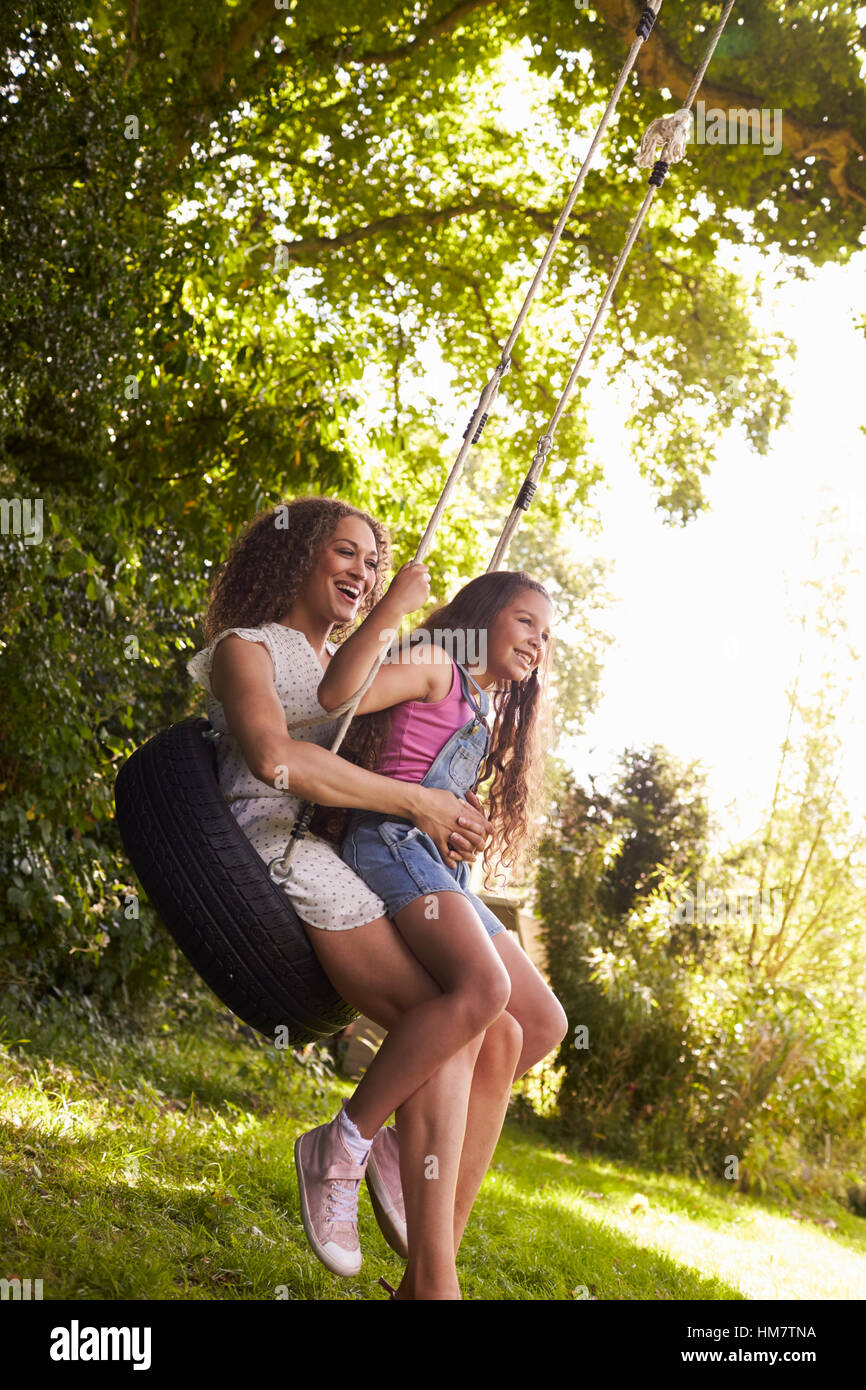 Mother And Daughter Sitting On Tire Swing In Garden Stock Photo - Alamy