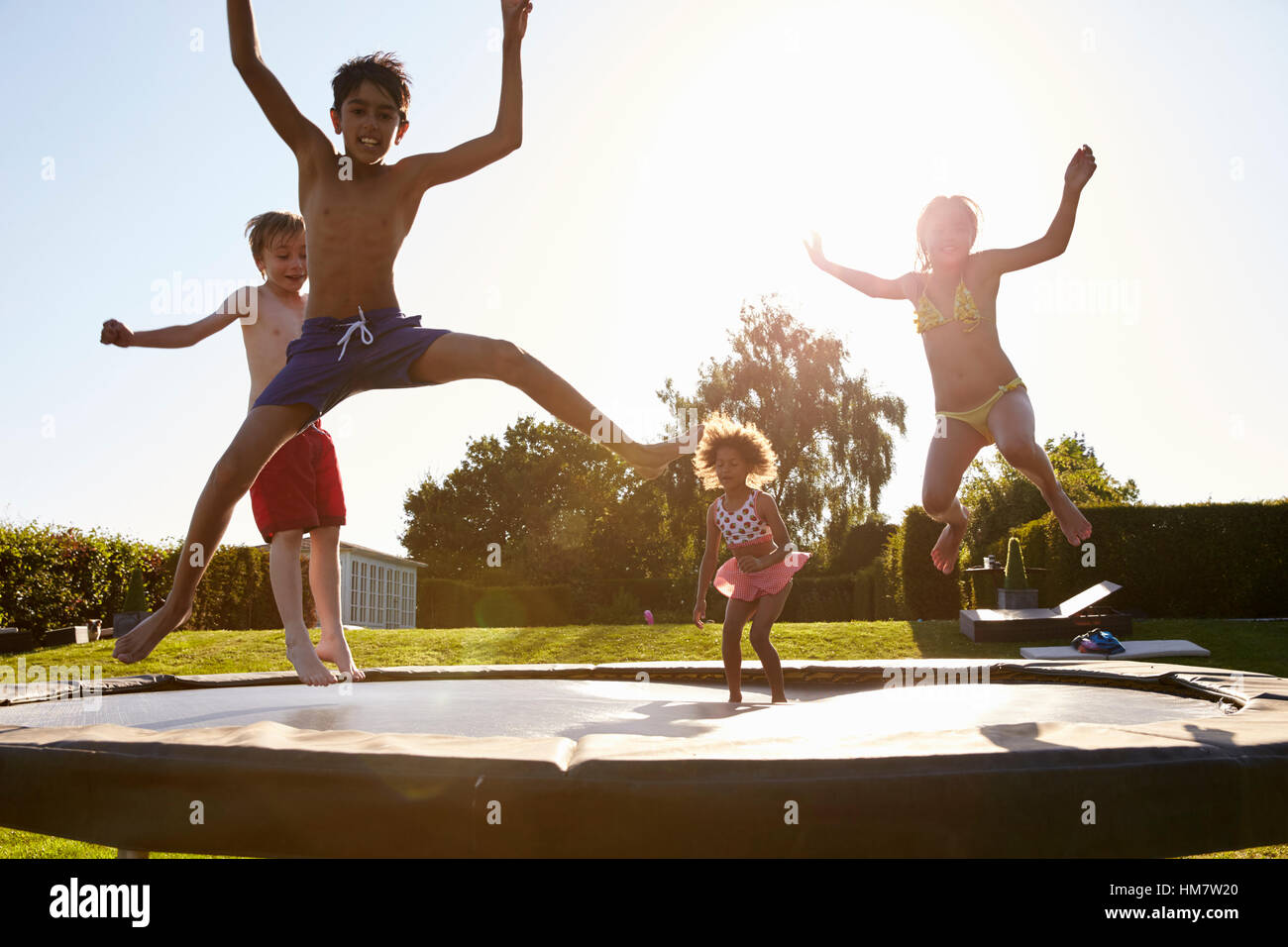 Group Of Children Having Fun Jumping On Outdoor Trampoline Stock Photo