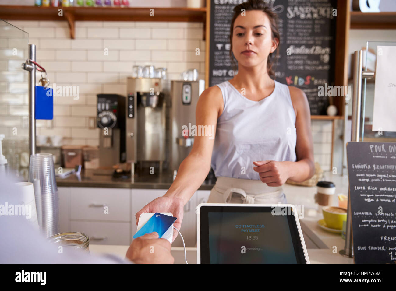 Waitress at coffee shop taking card payment from a customer Stock Photo