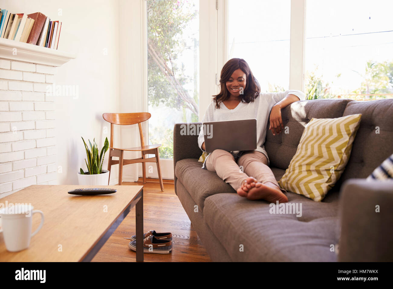 Woman Relaxing On Sofa At Home Using Laptop Stock Photo - Alamy
