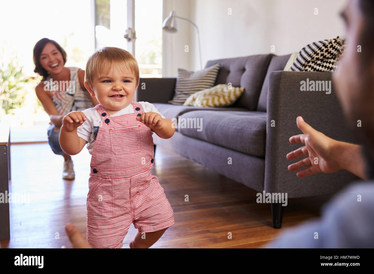 Parents Watching Baby Daughter Take First Steps At Home Stock Photo Alamy