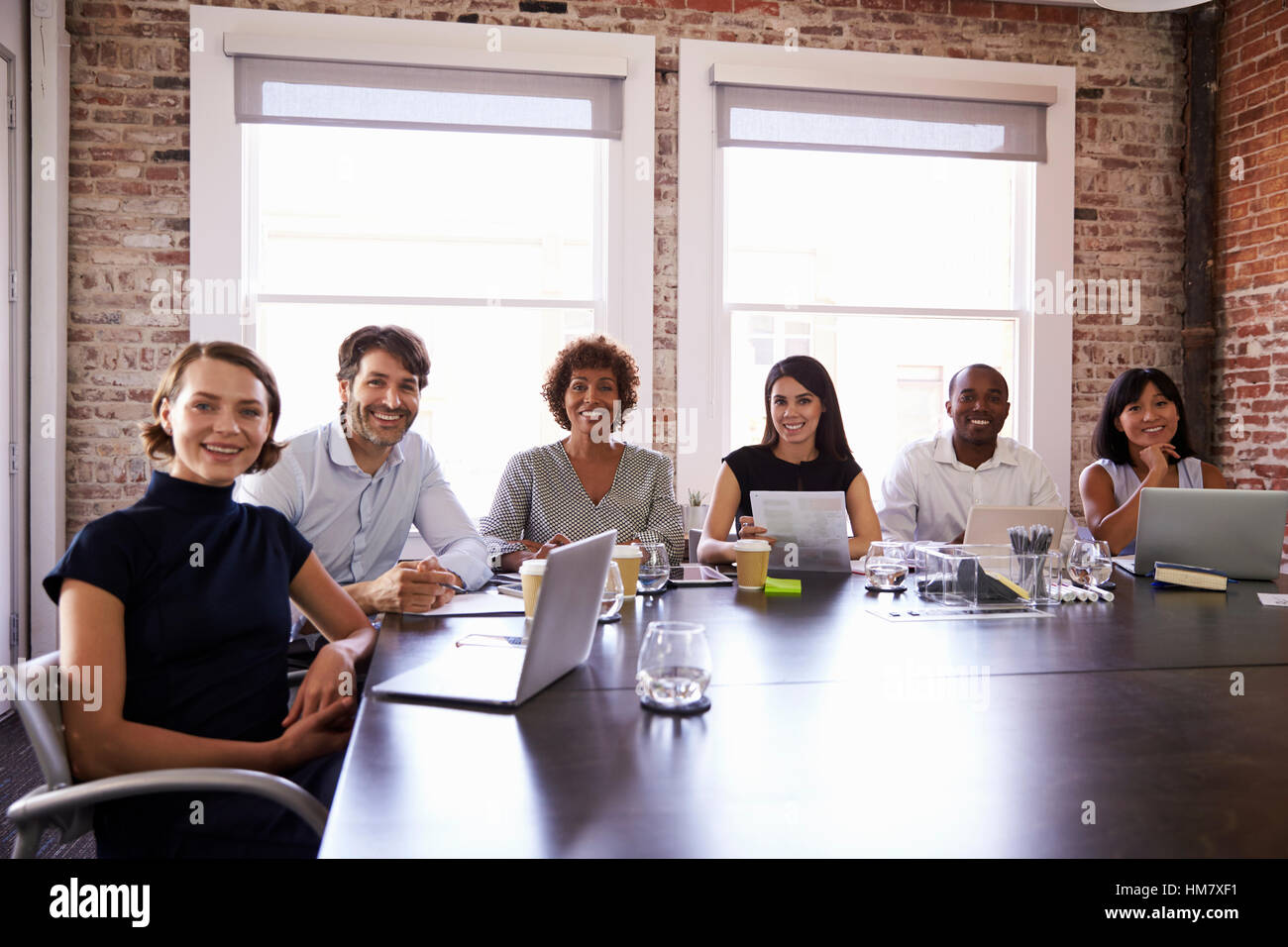 Portrait Of Businesspeople Sitting Around Boardroom Table Stock Photo