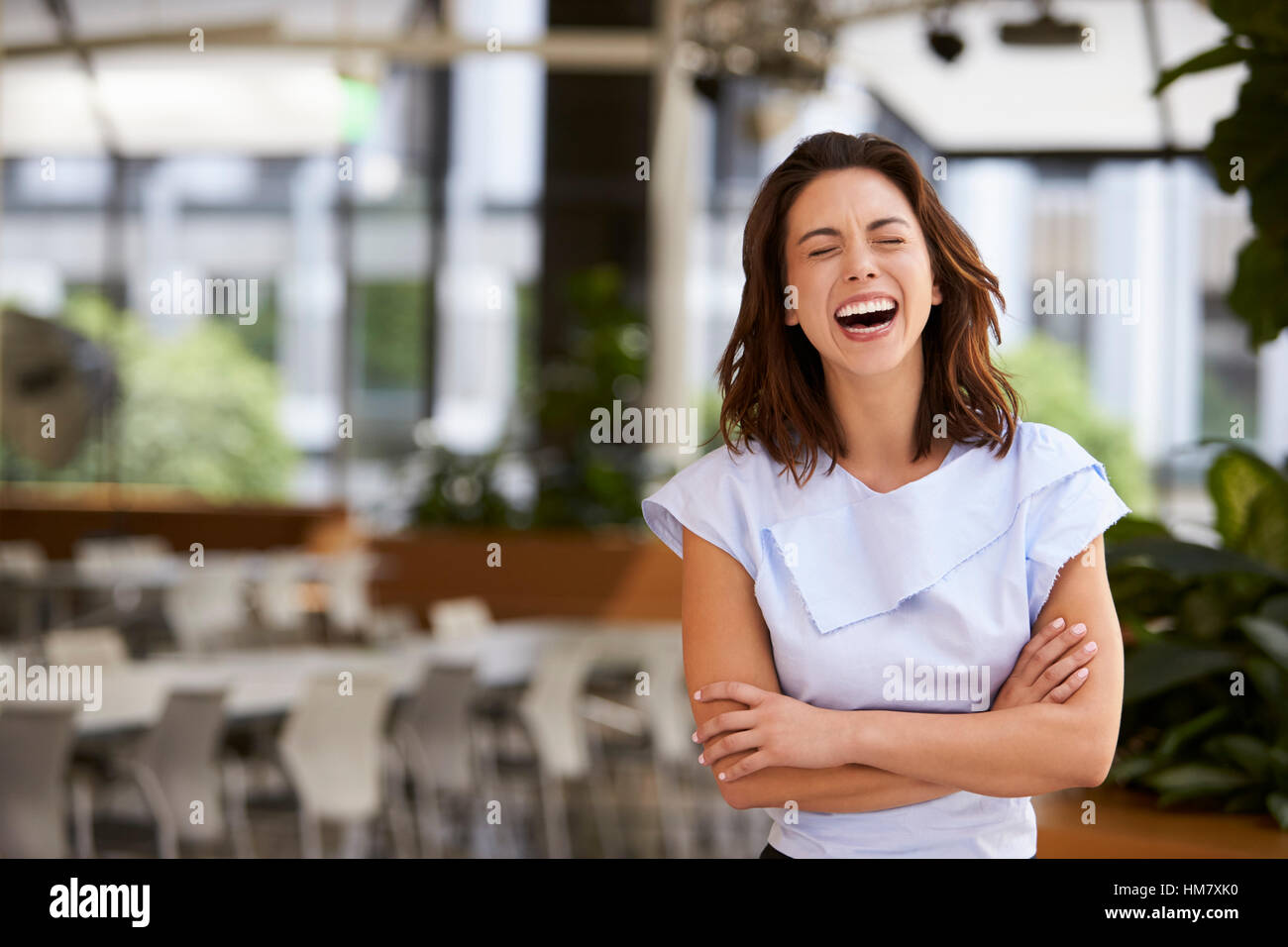 Laughing mixed race young businesswoman with arms crossed Stock Photo