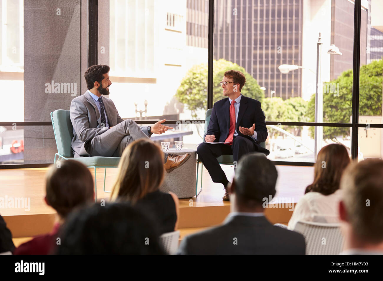 Speaker and interviewer talk in front of audience at seminar Stock Photo