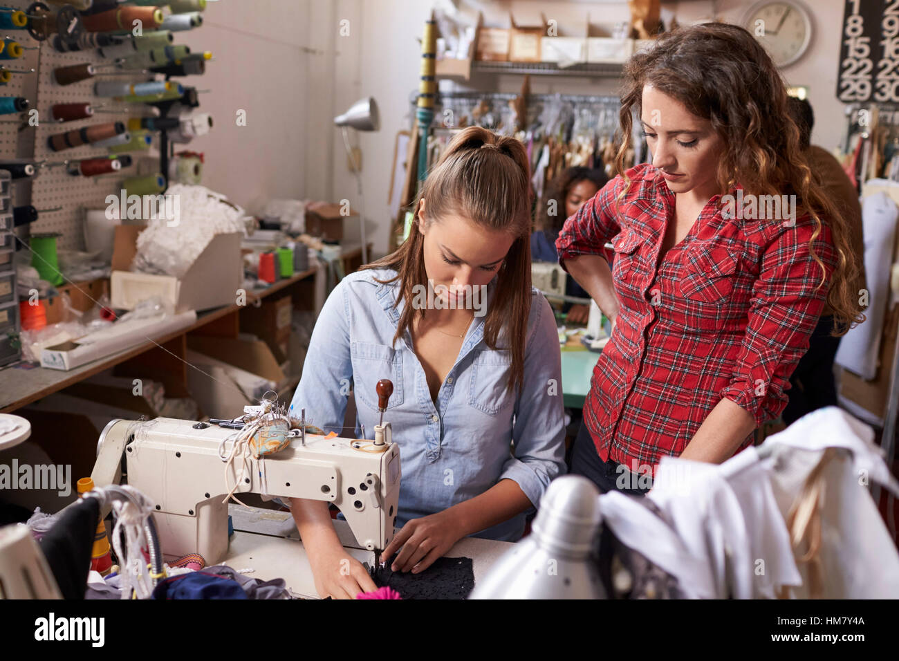 Colleague training machinist at a clothes design studio Stock Photo