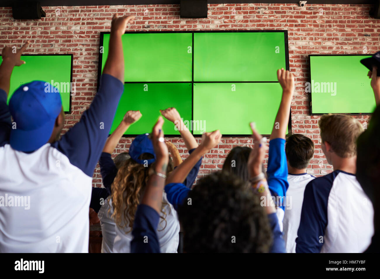 Rear View Of Friends Watching Game In Sports Bar Celebrating Stock
