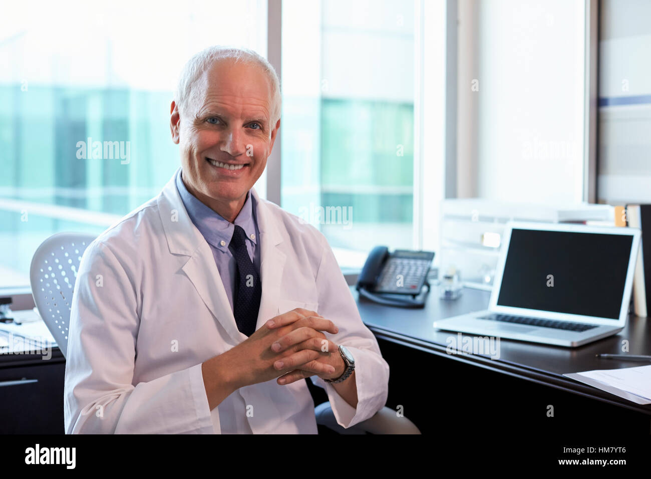 Portrait Of Doctor Wearing White Coat In Office Stock Photo