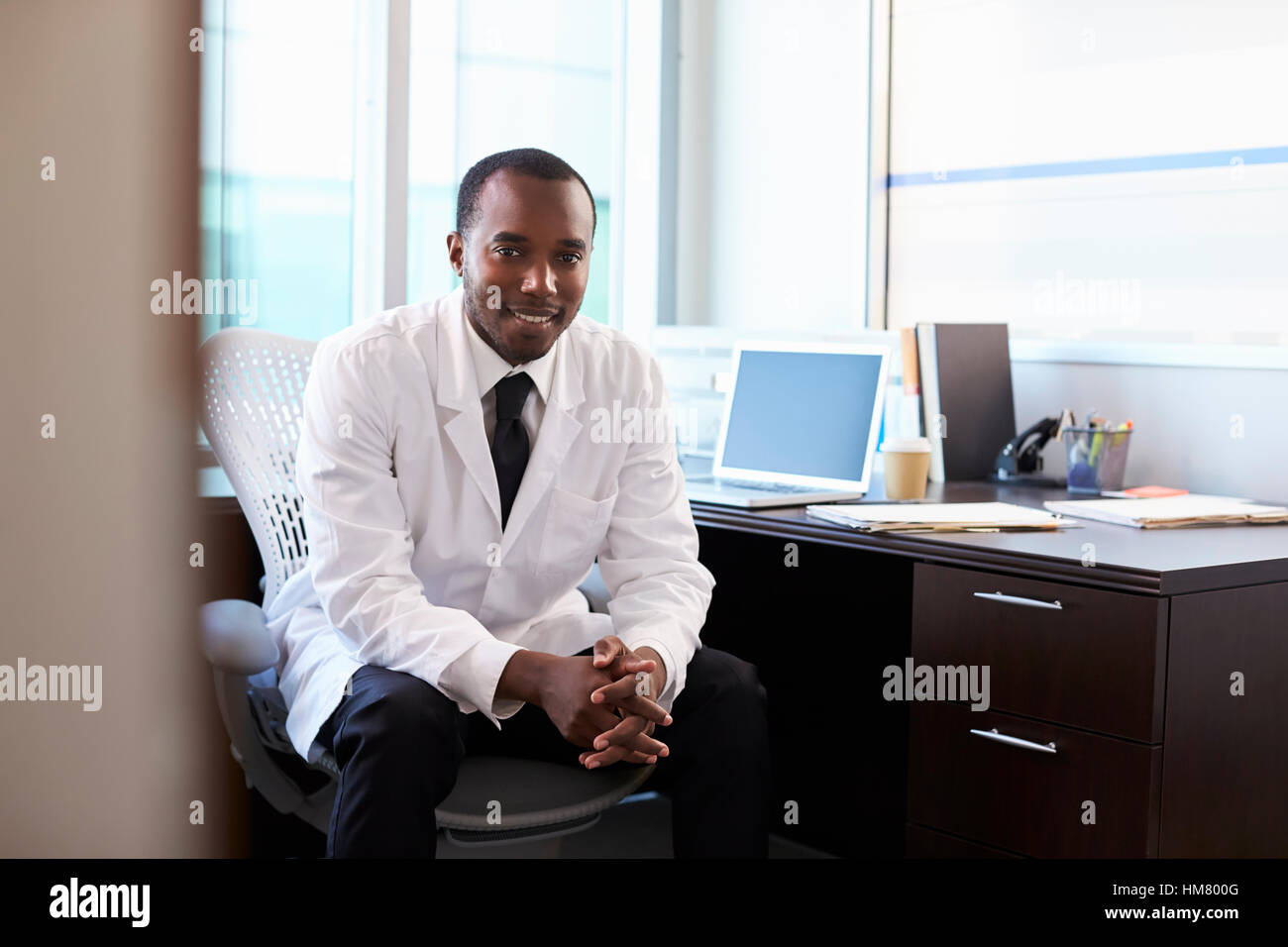 Portrait Of Doctor Wearing White Coat In Office Stock Photo