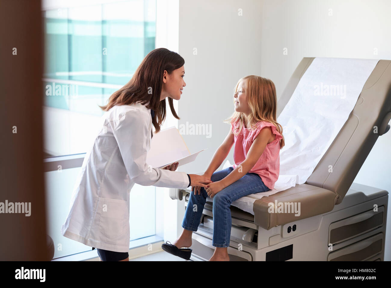 Pediatrician In White Coat With Child In Exam Room Stock Photo