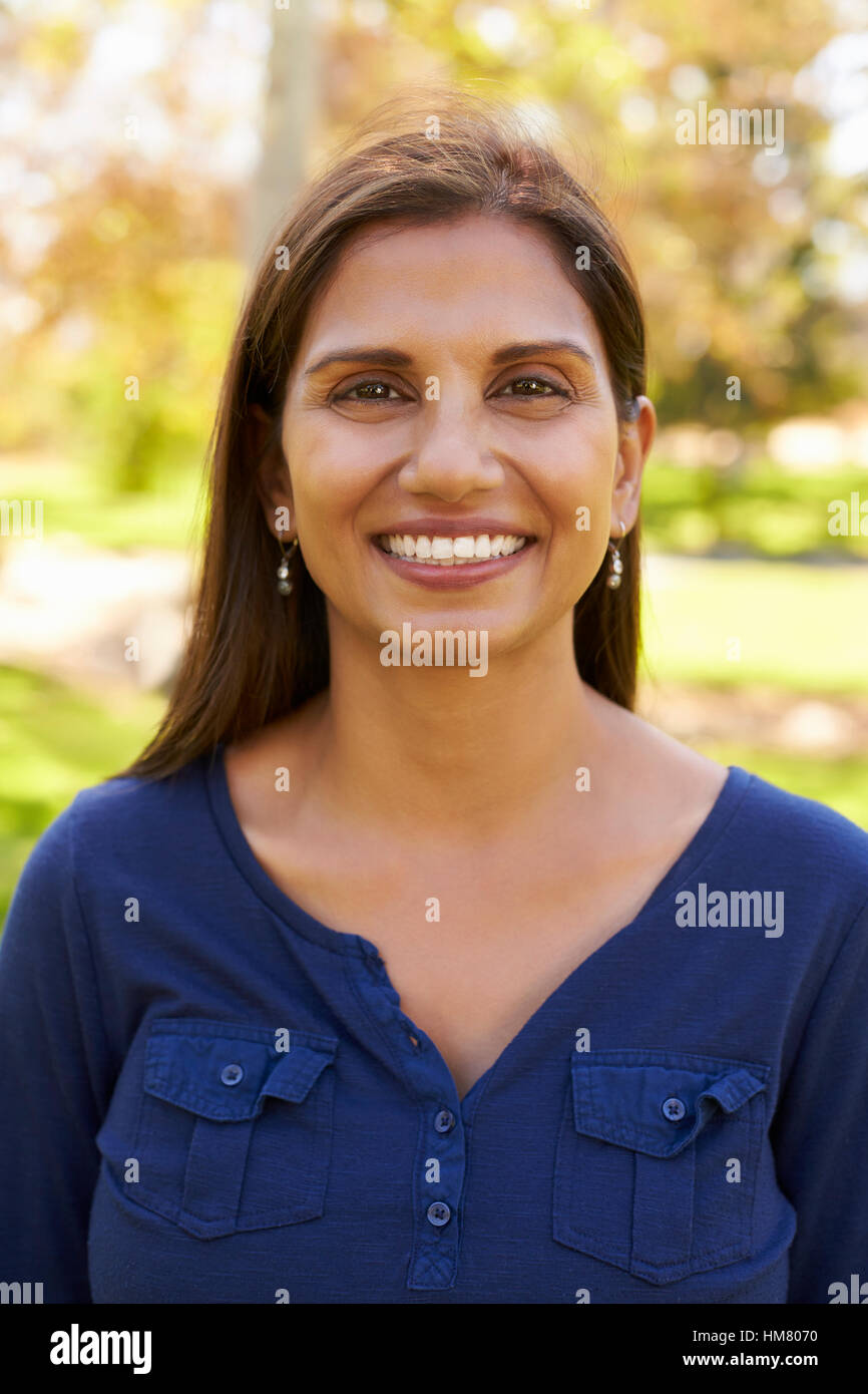 Smiling mixed race woman in park looking to camera, vertical Stock Photo