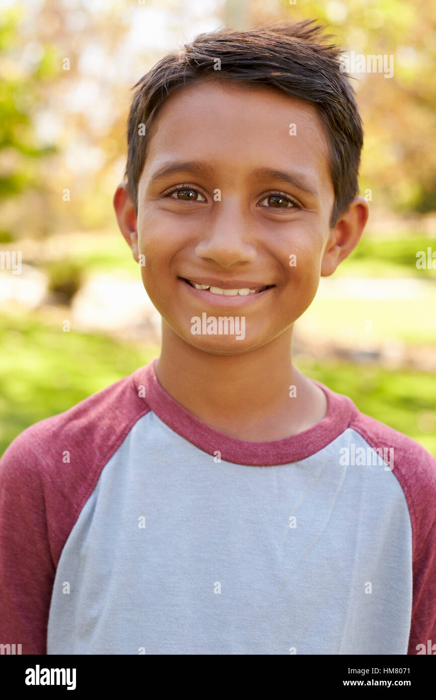Smiling mixed race boy in park looking to camera, vertical Stock Photo