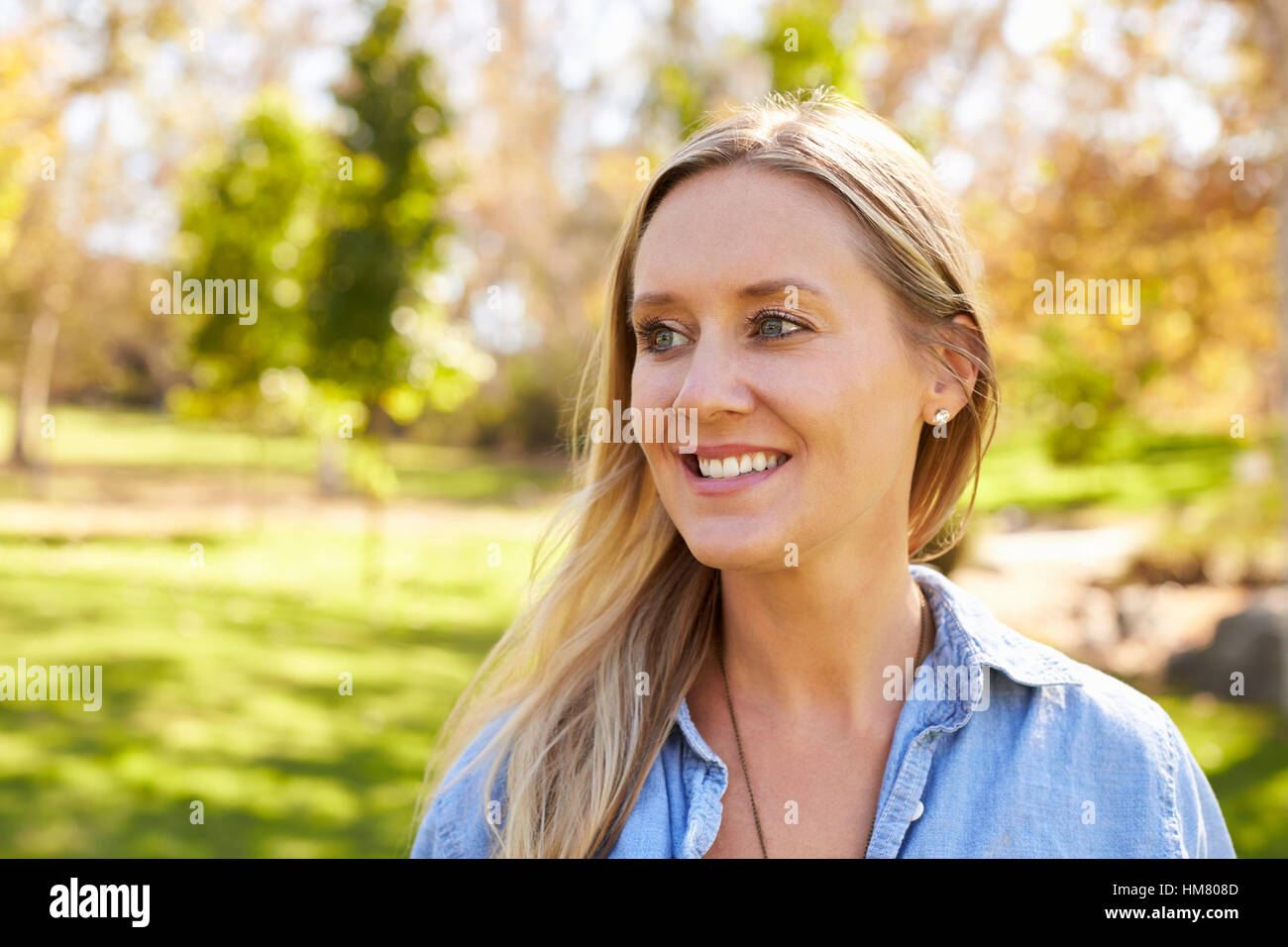 Mid thirties white woman looking away from camera in park Stock Photo