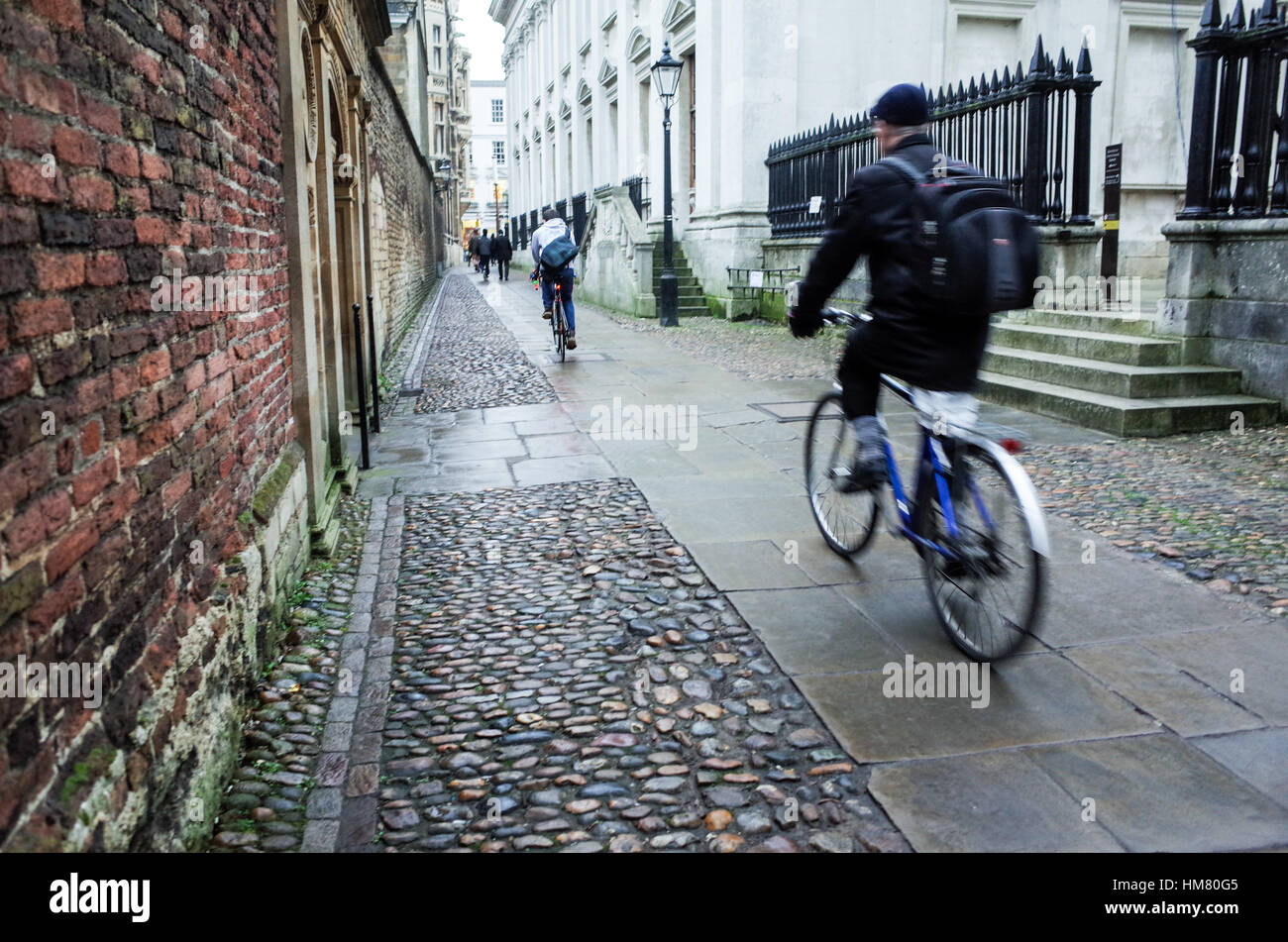 A commuter cycles past academic buildings in Cambridge City centre Stock Photo