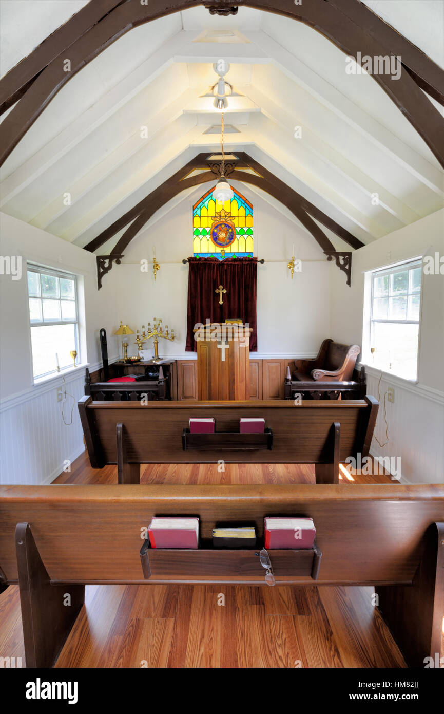 Small church interior with pews and pulpit, empty chapel with an arched ceiling and stained glass, inside view,mass books, cross. Stock Photo