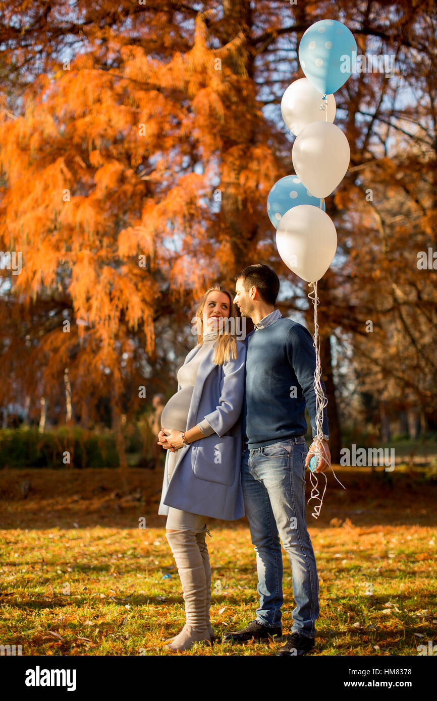 Young pregnant woman and man posing in autumn park with balloons in ...